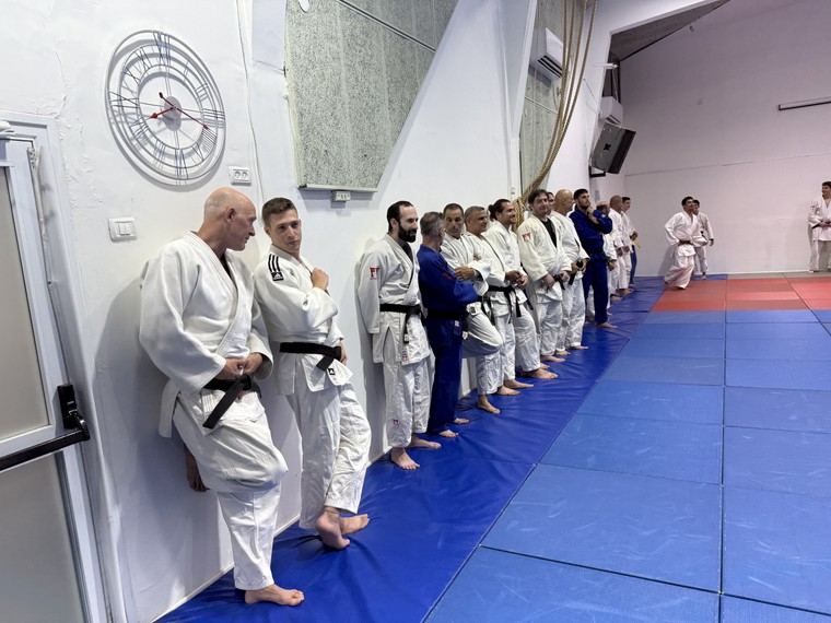 שורה של מתאמני ג׳ודופאן בחליפות ג׳ודו עומדים לאורך הקיר, מסתדרים בשורה לפני סייזה