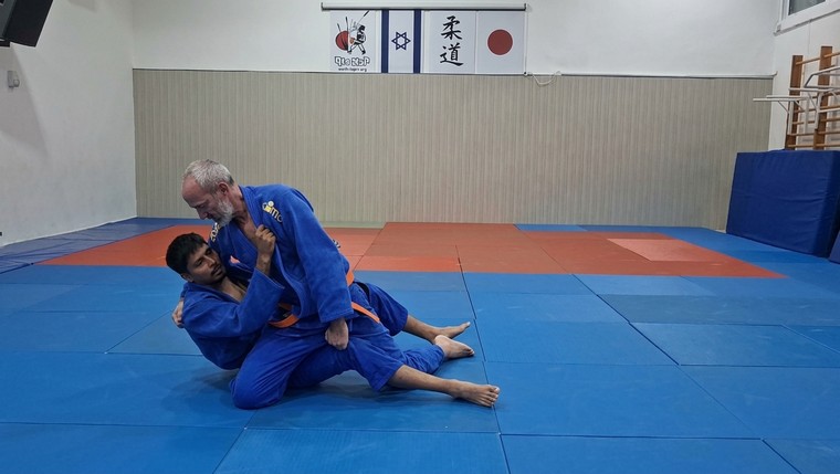 המאמן מדגים טכניקת קרקע (Ne-waza) על מתאמן, שניהם בחליפות ג׳ודו כחולות